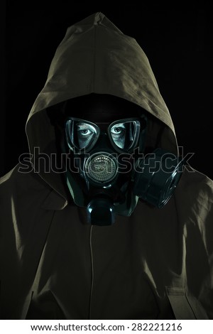 Bust of a man in chemical protection suit with a hood and a gas mask. Low key