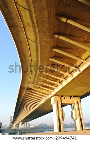 Underside of a winding yellow modern bridge, on a late sunny afternoon.