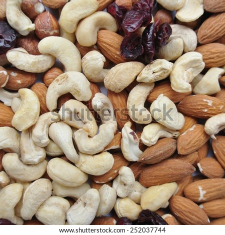 Close-up of a pile of various nuts - almonds, cashews and hazelnuts, and dried cranberries.  Healthy/clean eating concept.