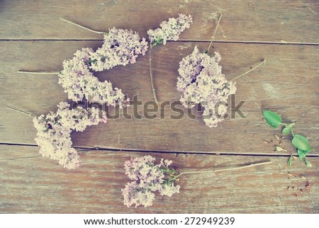 Vintage image of lilac flowers lying scattered on the rustic wooden table. Photo filtered in faded, washed out, retro style. Romantic vintage concept.