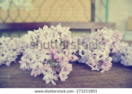 Vintage image of lilac flowers on the rustic wooden table. Photo filtered in faded, washed out, retro style. Romantic vintage concept.