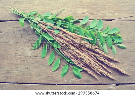 Dried grass and green leaves on rustic wooden table, shot from above. Image filtered in faded, washed out, retro style; nostalgic, vintage autumn concept.