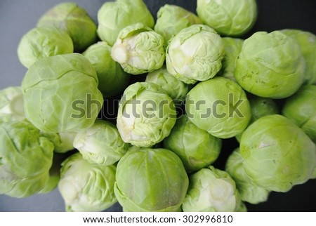 Closeup of a pile of fresh green Brussels sprouts on the black background. Healthy/clean eating concept; organic/unprocessed food; paleo diet.