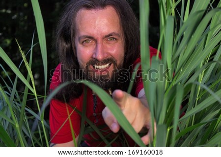 Long-haired man pointing out of high gras