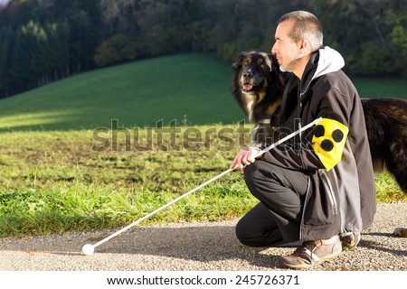 A blind man kneels next to his attentive guide dog