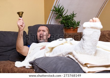 A man lying with a broken leg on the couch and ringing furiously for help