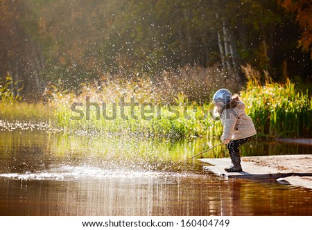 Funny little girl have a fun with a splash on the lake outdoors