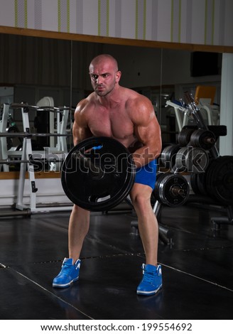 Muscular men exercising with weights. He is performing T bar rows for back muscle / Bodybuilder in the gym