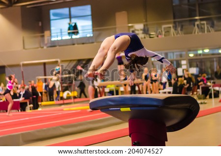 Young gymnast girl performing jump while practicing for the competition