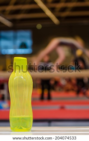 Bottle of water and little gymnast girl practicing in the background