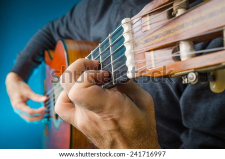 Closeup of a Man playing red classical guitar on concert, fingers, focus on left hand position.