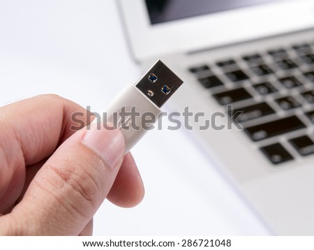 Men hand holding up a usb on a laptop background