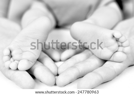 Mother hold baby leg in hand. Black and white image. Shallow focus
