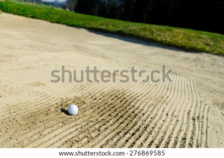 Golf ball is trapped in sand bunker on the golf course