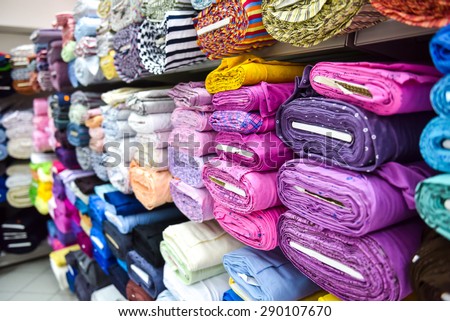 Rolls of fabric and textiles in a factory shop. Multi different colors and patterns on the market.
