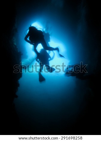 Silhouette of scuba divers in an underwater cave. Cave diving