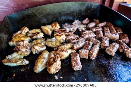 Barbecue grill on the propane gas grill. Chicken wings and cevapcici or country sausages.