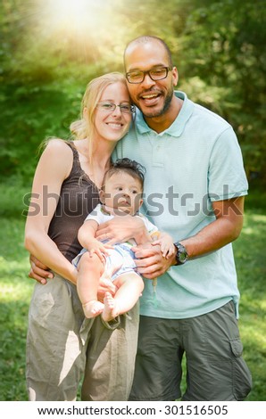 Happy interracial family is enjoying a day in the park. Little adopted mulatto baby boy. Adoption for young interracial family.