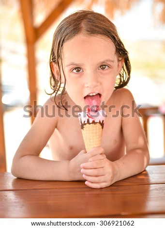 Little girl smiling and eating ice cream on vacation in a beach hut seaside after swimming in tropical sea. Vacation, lifestyle, happiness. No worries.