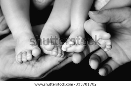 Little Baby Twins Feet in parents hands. Parenthood, family, twins, children and love concept.