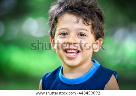 Happy mulatto boy child is smiling enjoying adopted life. Portrait of young boy in nature, park or outdoors. Concept of happy family or successful adoption or parenting.