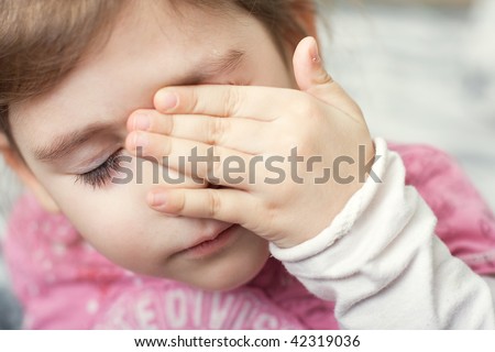 little girl covering her eyes with her hand
