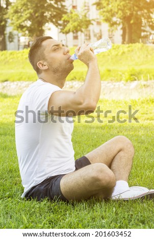 Thirsty sport man having a break drinking a bottle of water