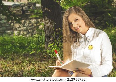 Young brunette woman writing in nature