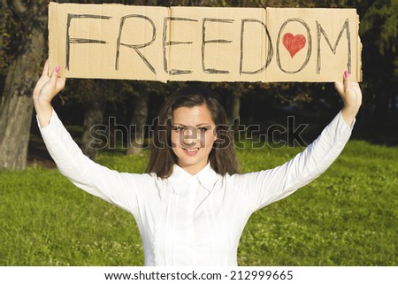 Smiling girl holding paper with inscription for freedom. Enjoy freedom young women in nature.