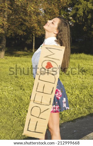 Smiling girl holding paper with inscription for freedom. Enjoy freedom young women in nature.