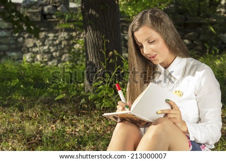 Student sitting in the park and writes something