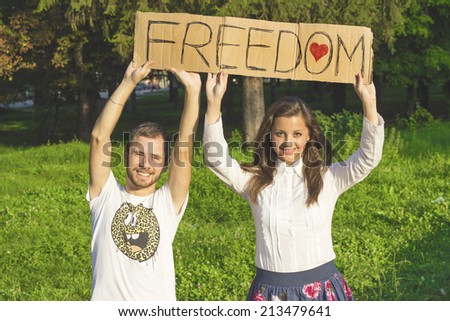 Smiling women and man holding paper with inscription for freedom. Enjoy freedom young women in nature.