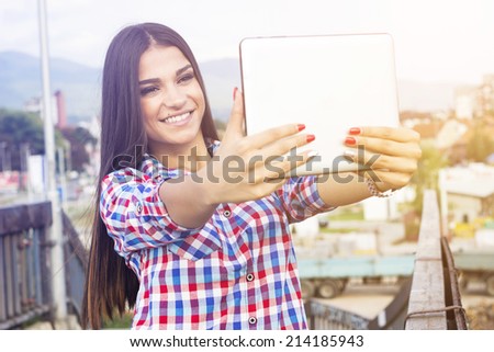 Beautiful, smiling woman take a picture of herself with digital tablet. Selfie style.