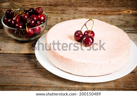 chocolate-cherry cheesecake on a dark wood background. toning. selective focus on the cherry on top of the cheesecake