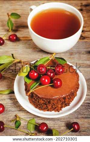chocolate cake mini with cherries on a dark wood background. toning. selective focus on the cherry on the cake