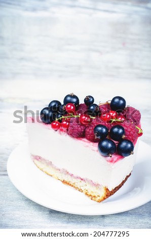 cheesecake with raspberries, red and black currants on a white wood background. toning. selective focus on berries