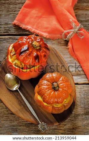 baked pumpkin stuffed with beef and vegetables on a dark wood background. tinting. selective focus on the bottom pumpkin