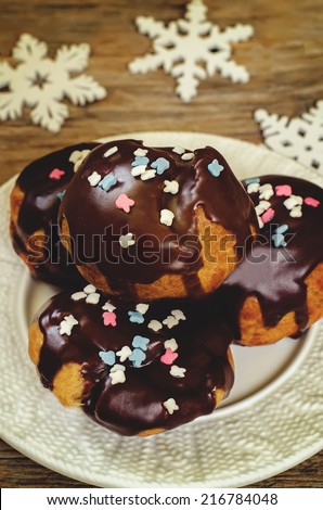 profiteroles with chocolate icing and colored powder on a dark wood background. tinting. selective focus on the middle of top profiterole