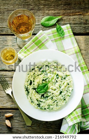 risotto with spinach on a dark wood background. tinting. selective focus on spinach