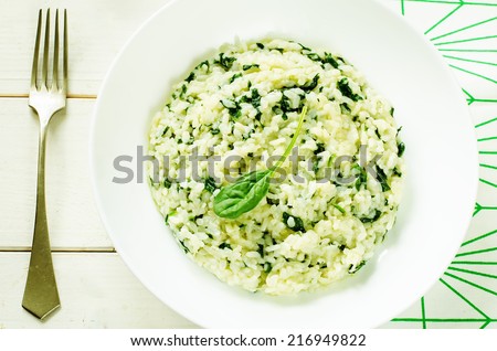 risotto with spinach on a light wood background. tinting. selective focus on spinach