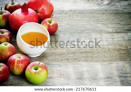 apples, honey and pomegranates on a dark wood background, traditional food for the Jewish new year. Rosh Hashana. selective focus on the middle of the honey