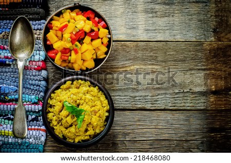 salad of mango and tomato with red lentils with curry and dates on a dark wood background. tinting. selective focus on the middle of salad