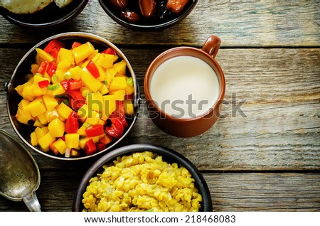 salad of mango and tomato with red lentils with curry and dates on a dark wood background. tinting. selective focus on the middle of salad