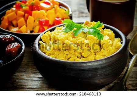 red lentils with curry and dates and a salad of mango and tomato on a dark wood background. tinting. selective focus on parsley