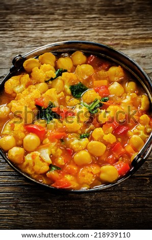 curry chickpea with cauliflower and vegetables on a dark wood background. tinting. selective focus on the middle of curry