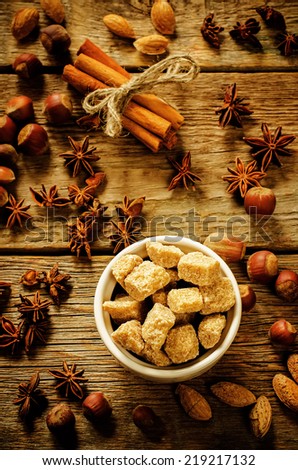 cane sugar with nuts, cinnamon and star anise on a dark wood background. tinting. selective focus on the cane sugar. background with copy space