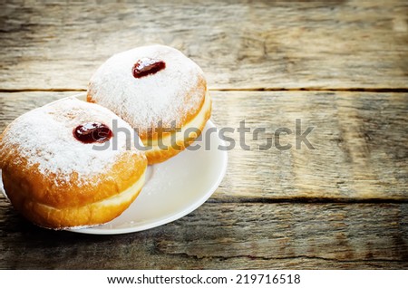 fresh doughnuts with jam on a dark wood background for Hanukkah. tinting. selective focus on the front donut