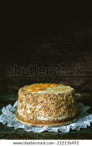 cake with almonds; cream, cheesecake and caramelised mango on a dark wood background. tinting. selective focus on the front of the cake