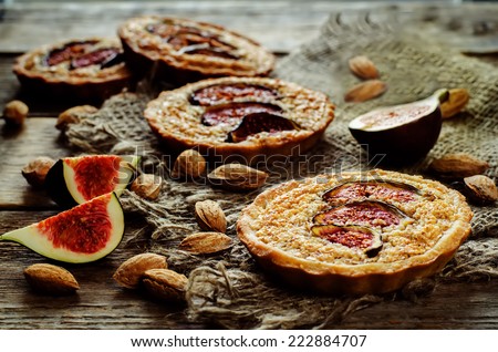 tartlets with Fig and almond cream (Frangipane) on a dark wood background. tinting. selective focus on the middle of the front tartlet