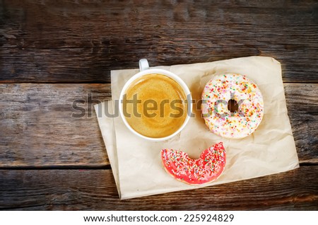 Donuts and coffee on a dark wood background. toning. selective focus on red donut
